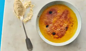 Creme brulee mit karamellisierter Zuckerkruste und Bläschen, daneben ein Löffel mit feinem Zucker.