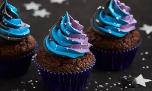 Drei Schoko-Cupcakes mit blau-lila Sternen-Frosting, inspiriert von einem Galaxie-Cupcake-Rezept.