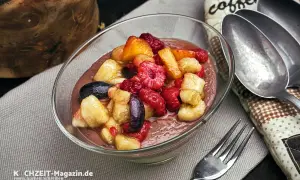 Schüssel mit cremigem Dessert und frischem Obstsalat aus Himbeeren, Bananen und Aprikosen. Perfekt für ein leichtes obstsalat rezept.