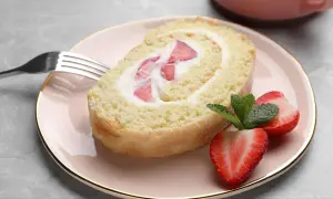 Ein Stück Biskuitrolle mit Erdbeeren und Sahne, perfekt für ein leichtes Dessert. Dieses Biskuitrolle Rezept ist ein Genuss!