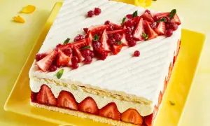 Rechteckiger Kuchen mit Erdbeeren und roter Johannisbeere auf leichter Erdbeer-Buttercreme, verziert mit Minze.