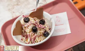 Ein süßes Delfino Eis mit Kirschen und Waffelherzen, serviert auf einer rosa Schale.