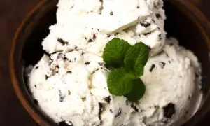 Cremiges Stracciatella Eis mit Schokoladenstückchen in einer Holzschale, garniert mit frischer Minze. Ein einfaches Stracciatella Eis Rezept zum Nachmachen.