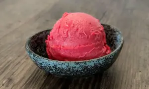 Ein Löffel Kirsch Eis in einer Schale auf Holztisch.