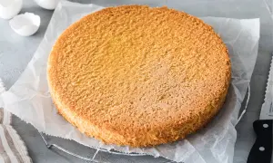 Ein goldbrauner Biskuitboden, perfekt für jedes Biskuitteig Rezept. Daneben leere Eierschalen und ein Messer.