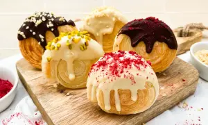 Fünf köstliche New York Rolls, verlockend mit Schokolade, Pistazien und roten Streuseln verziert, auf einem Holzbrett.