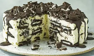 Cremige Oreo Torte mit Schokoladenguss und zerbröselten Keksen obendrauf. Ein Stück ist bereits angeschnitten.