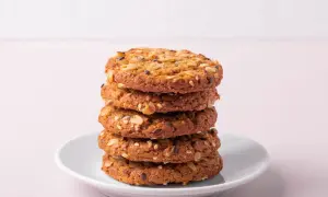 Ein Stapel knuspriger Kekse ohne Zucker, verfeinert mit Haferflocken und Samen, auf einem weißen Teller.