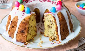 Ein Gugelhupf mit Schokoladenstückchen, Zuckerguss und bunten Ostereiern. Dieses Gugelhupf Rezept ist perfekt für Ostern.