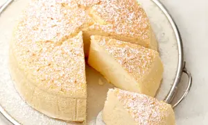 Ein luftiger, fluffiger japanischer Cheesecake, bestäubt mit Puderzucker, auf einer Servierplatte.