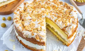 Eine köstliche Stachelbeer Baiser Torte, mit Baiserhaube und Mandelblättchen, daneben ein Stück Torte mit saftiger Füllung.