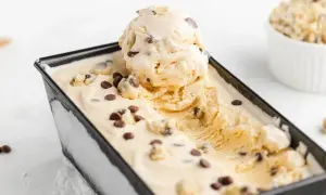 Cremiges Cookie Dough Eis mit Schokoladenstückchen in einer schwarzen Form, eine Kugel ist herausgenommen.