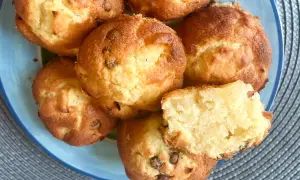 Saftige apfel muffins mit Schokoladenstückchen auf einem blauen Teller. Einer ist zerbrochen und zeigt das weiche Innere.