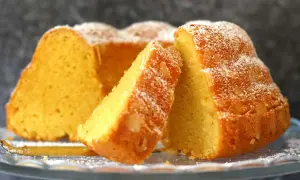 Ein saftiger Kuchen mit vielen Eiern, bestäubt mit Puderzucker, auf einem Glasständer.
