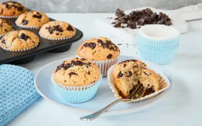 Schokoladenmuffins, frisch gebacken nach einem einfachen Muffins Rezept. Ein Muffin ist angeschnitten und zeigt die saftige Krume.