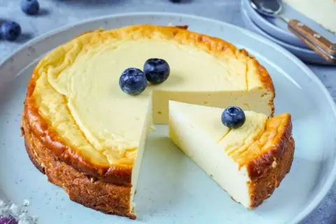 Ein cremiger Käsekuchen, perfekt für Diabetiker, mit frischen Blaubeeren garniert. Ein Stück wurde bereits entnommen.