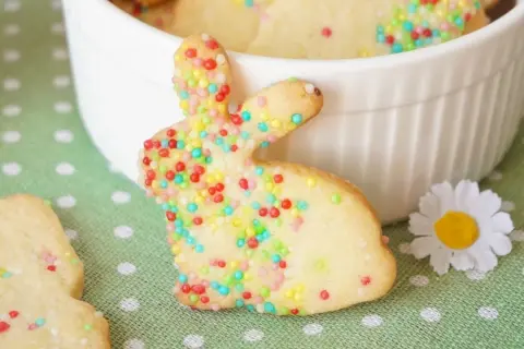Bunte Osterkekse zum Ausstechen in Hasenform, verziert mit Zuckerstreuseln. Ein süßer Gruß für das Osterfest.