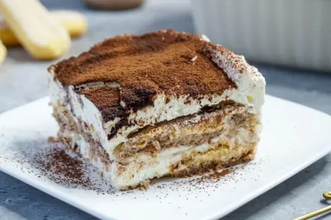Ein Stück cremiges Tiramisu, bestäubt mit Kakao, perfekt für kleine Genießer.