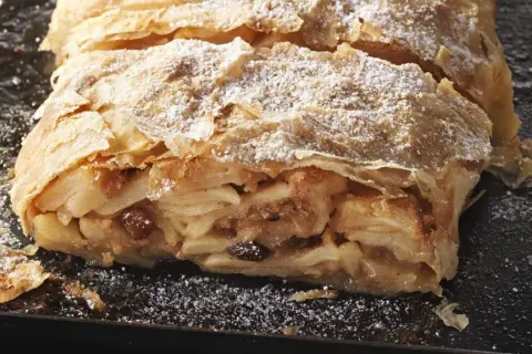 Ein saftiger Apfelstrudel, bestäubt mit Puderzucker, wartet darauf, nach diesem Rezept gebacken zu werden.