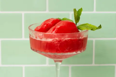 Erfrischendes Wassermelonen Sorbet in einem eleganten Glas, garniert mit Minze. Perfekt für heiße Tage.