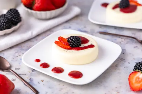Cremige Panna Cotta, perfekt zubereitet im Thermomix, garniert mit frischen Beeren und Erdbeersauce. Ein Genuss für Augen und Gaumen.