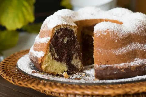 Ein saftiger Gugelhupf Marmor, bestäubt mit Puderzucker, wartet auf seinen Anschnitt.