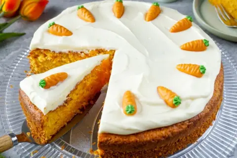 Ein saftiger Karottenkuchen mit weißem Zuckerguss und kleinen Marzipanmöhren. Perfekt für ein Osterkuchen Rezept!