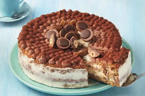 Eine köstliche Toffifee Torte, verziert mit Kakao und Toffifee-Pralinen, wird angeschnitten.