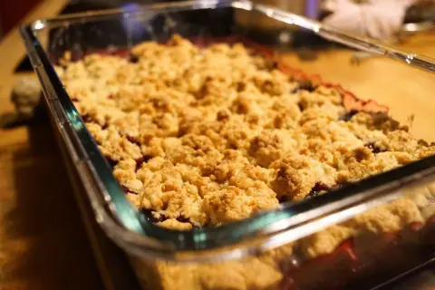 Frisch gebackener Himbeer Crumble in einer Glasform. Die goldbraune Kruste duftet verlockend nach Beeren und Streuseln.