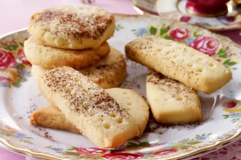 Leckeres Shortbread-Rezept: goldbraune Kekse, rund und rechteckig, mit Zimt und Zucker bestreut, auf einem floralen Teller.