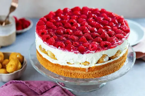 Eine köstliche Windbeuteltorte mit Himbeeren, geschichtet mit Sahne und Biskuit, verlockt zum Genuss.