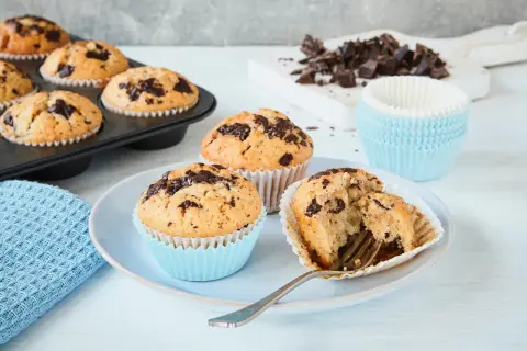 Schokoladenmuffins, frisch gebacken nach einem einfachen Muffins Rezept. Ein Muffin ist angeschnitten und zeigt die saftige Krume.
