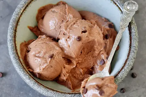 Cremiges schokoladen eis mit zartschmelzenden Schokostückchen in einer rustikalen Schale, bereit zum Genießen.