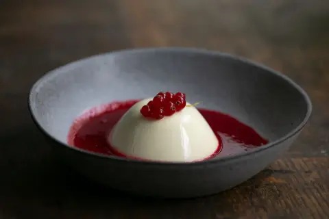 Cremige Panna Cotta mit roter Johannisbeersauce, ein köstliches Rezept für ein leichtes Dessert.