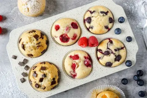 Saftige Muffins mit Schokolade, Himbeeren und Blaubeeren im Muffinblech. Ein köstliches Muffins Rezept für jeden Anlass.