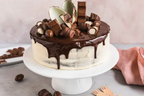 Eine köstliche Kinderschokolade Torte mit Schokoladenglasur und vielen Schokoriegeln und Kugeln verziert.
