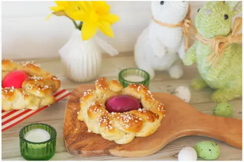 Zwei geflochtene Osterkränze mit gefärbten Eiern, bereit zum Osterfrühstück. Das Backen von Osterkränzen ist eine schöne Tradition.
