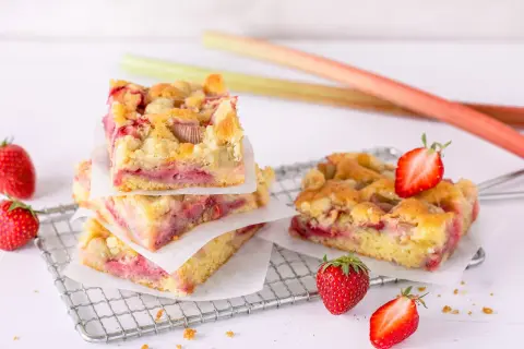Saftiger Erdbeer Rhabarber Kuchen mit Streuseln, garniert mit frischen Erdbeeren.