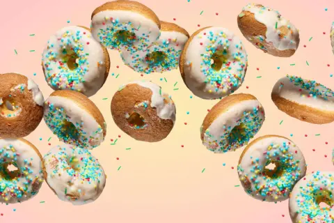 Bunte Donuts mit weißer Glasur und Streuseln schweben im Bild. Ein köstliches Rezept für selbstgemachte Donuts.