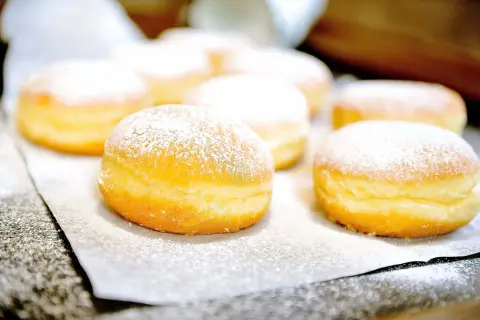 Frisch gebackene Krapfen, mit Puderzucker bestäubt, warten auf das Krapfen Rezept.