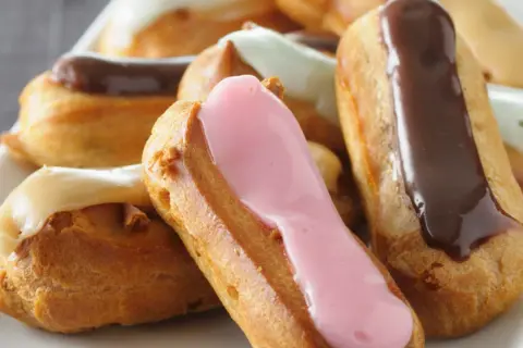 Bunte Éclairs mit Schokoladen-, Erdbeer- und Vanilleglasur. Ein köstliches Éclair-Rezept zum Nachbacken.
