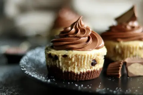 Schokoladen-Cheesecake-Muffins mit zarter Füllung und cremigem Topping, garniert mit Schokostückchen.