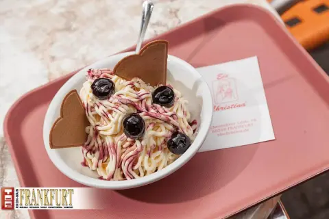 Ein süßes Delfino Eis mit Kirschen und Waffelherzen, serviert auf einer rosa Schale.