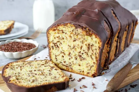 Ein saftiger Marmorkuchen mit Schokoladenglasur, perfekt zum Kuchen backen. Daneben liegen Schokostreusel und ein Messer.
