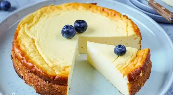 Ein cremiger Käsekuchen, perfekt für Diabetiker, mit frischen Blaubeeren garniert. Ein Stück wurde bereits entnommen.
