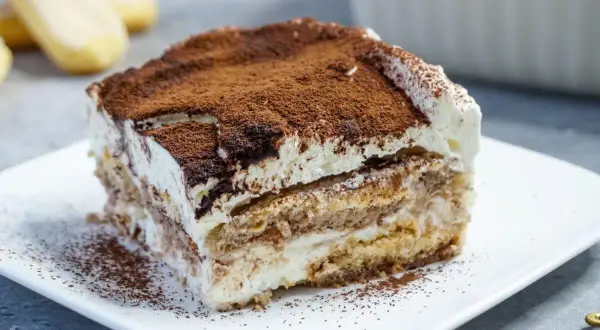 Ein Stück cremiges Tiramisu, bestäubt mit Kakao, perfekt für kleine Genießer.