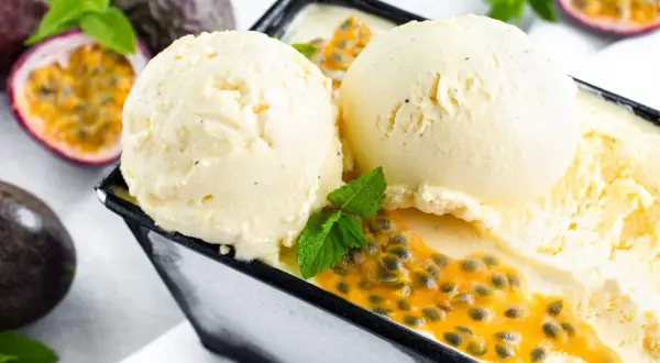 Zwei Kugeln cremiges Maracuja Eis mit frischer Passionsfrucht und Minze. Ein tropischer Genuss!