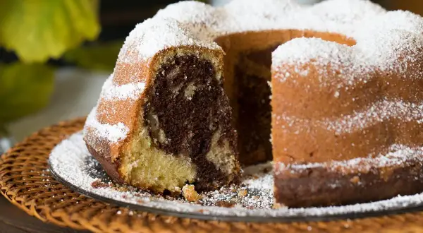 Ein saftiger Gugelhupf Marmor, bestäubt mit Puderzucker, wartet auf seinen Anschnitt.