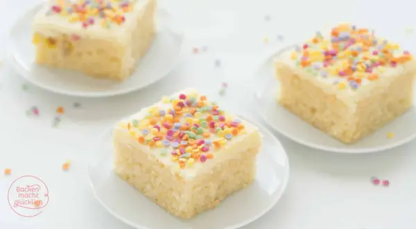Drei Stücke saftiger konfetti kuchen mit weißer Glasur und bunten Streuseln auf weißen Tellern.