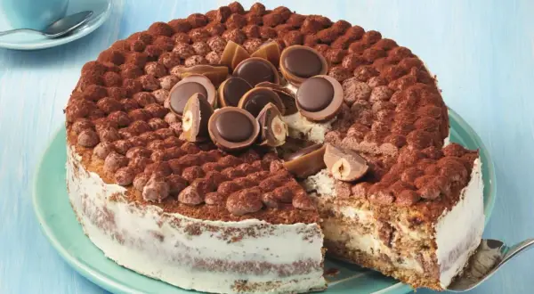 Eine köstliche Toffifee Torte, verziert mit Kakao und Toffifee-Pralinen, wird angeschnitten.